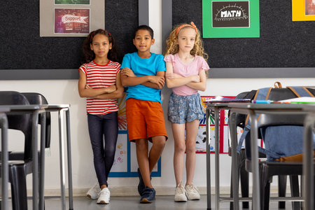 In school, diverse group of young students standing together in the classroom. They have casual...
