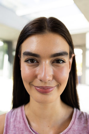 Close-up of a teenage Caucasian girl smiling at the camera. Her cheerful expression brightens the...