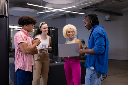 In modern office, diverse young team sharing ideas, laughing. Biracial woman with curly hair,...