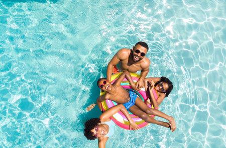 Diverse family enjoys a sunny day in the pool. Smiles radiate as they share a fun and relaxing...