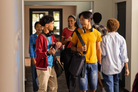 Teenagers walking in high school hallway, talking and carrying backpacks and books. Education, teens, friendship, students, high high school, conversationの写真素材