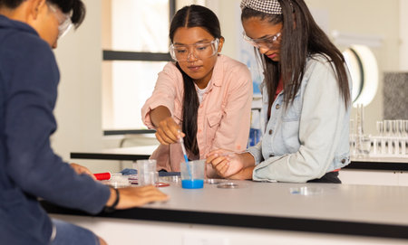 In high school, teenagers conducting science experiment with safety goggles in classroom. Education, chemistry, learning, students, lab, STEMの写真素材