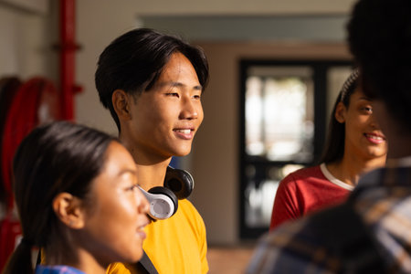 Teenager with headphones smiling and talking with friends at high school. group, communication, laughter, socializing, youth, back to high schoolの写真素材