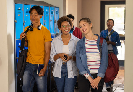 Walking in high school hallway, teenagers smiling and carrying backpacks. Students, education,...