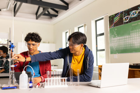 In high school, teenagers conducting science experiment with lab equipment and laptop. Education,...