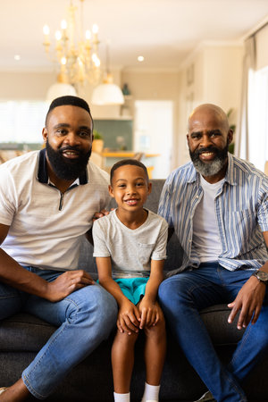 Smiling family sitting on couch, two men and young boy enjoying time together. happiness, bonding,...