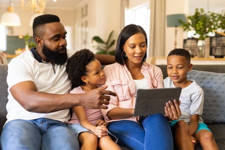 Family sitting on couch, using tablet together, enjoying quality time at home. bonding, technology,...