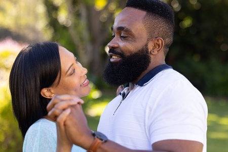 "Couple holding hands and smiling at each other in outdoor setting. Romance, relationship, love, happiness, bonding, affectionの写真素材