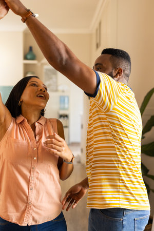 "Dancing together, couple enjoying quality time at home in casual outfits, in kitchen. Togetherness, lifestyle, bondingの写真素材