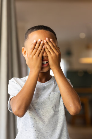 Playing peekaboo, boy covering eyes with hands and smiling indoors. childhood, playful, fun, game,...