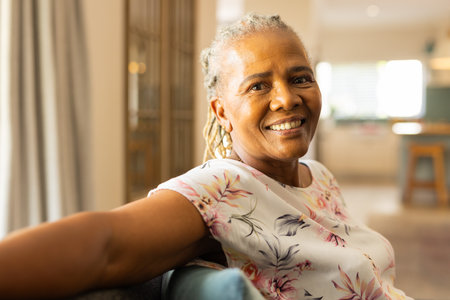 Smiling senior woman relaxing on couch at home, enjoying leisure time indoors. Relaxation, comfort,...