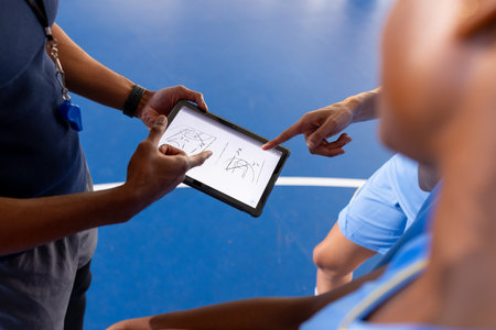 Basketball male coach using tablet to discuss game strategy with players. team, technology, discussion, sportsの写真素材
