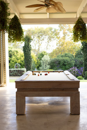 Playing pool on billiards table in bright, open patio area. recreation, leisure, game, outdoors, fun, relaxationの写真素材