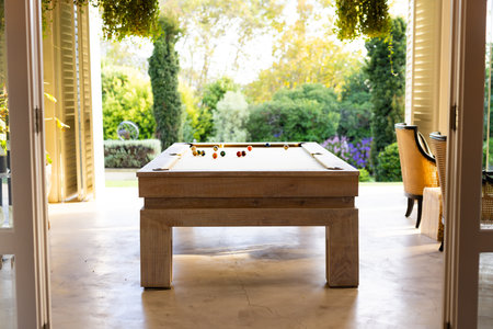 Playing billiards on pool table in bright, open indoor-outdoor space. leisure, recreation, game,...