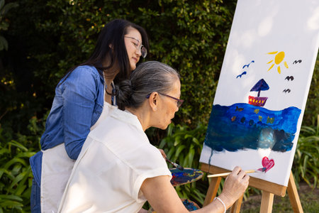 Painting on canvas, asian granddaughter and grandmother creating artwork together. creativity,...