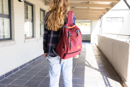 Walking in school hallway, teenage girl with backpack heading to class. Education, learning,...