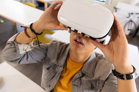 Using VR headset, asian teenage boy exploring virtual reality in school classroom. Education,...