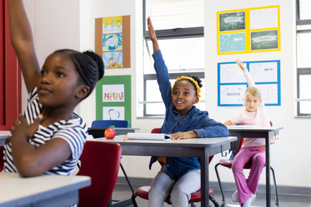 In school, multiracial girls raising hands to answer questions in classroom. Education, learning,...