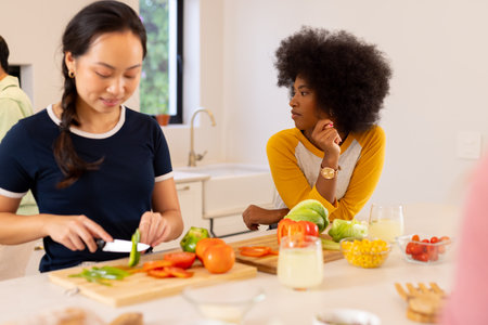 Preparing vegetables, diverse friends cooking together in modern kitchen. teamwork, culinary, fun,...