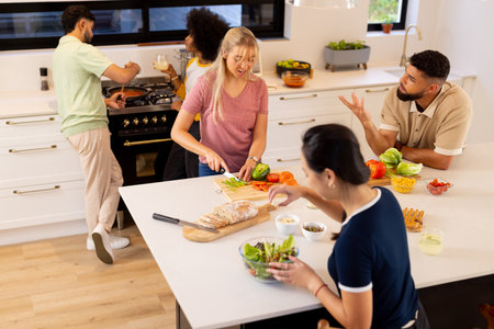 Friends preparing meal together, chopping vegetables and making salad in kitchen. Cooking, diverse friendship, culinary, meal preparation, healthy eating, lifestyleの写真素材