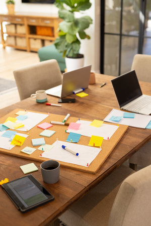 Working from home, laptops and tablets on table with sticky notes and coffee cups. Remote work, home office, productivity, technology, devices, organizationの写真素材