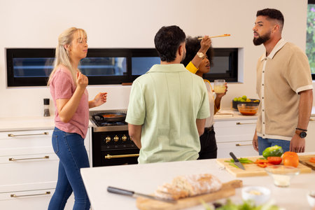 Cooking together, group of diverse friends enjoying food and conversation in kitchen. Friendship,...