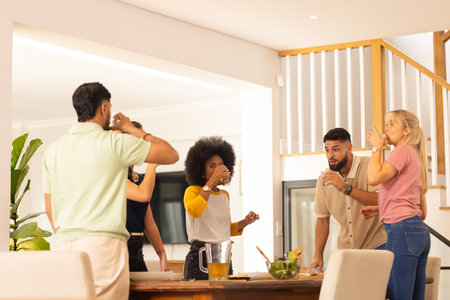 Friends drinking juice together in modern kitchen, enjoying casual gathering. Friendship, bonding,...