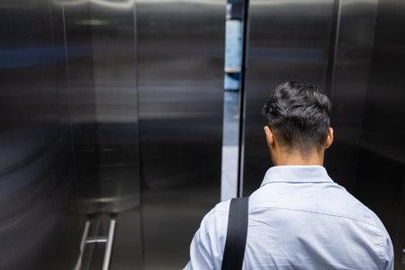 Entering elevator, businessman with shoulder bag heading to office for work, copy space. corporate, professional, commute, workwear, briefcase, transportationの写真素材