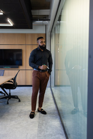 African American Businessman in office writing on glass wall during meeting, holding marker. teamwork, brainstorming, collaboration, corporate, strategy, planningの写真素材