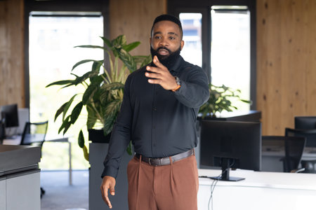 Gesturing while discussing project with colleagues, African American businessman in office....
