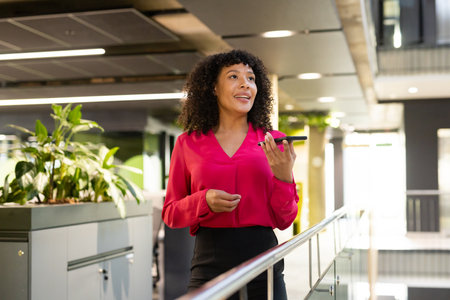 Holding smartphone, businesswoman walking and talking in modern office building. corporate,...