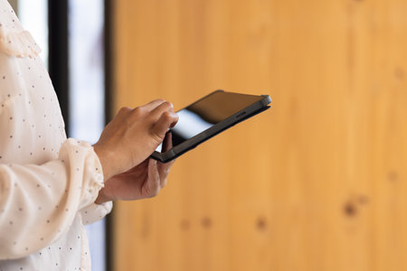 Using tablet, person working on business tasks in modern office setting. Technology, productivity, professional, digital, workspaceの写真素材