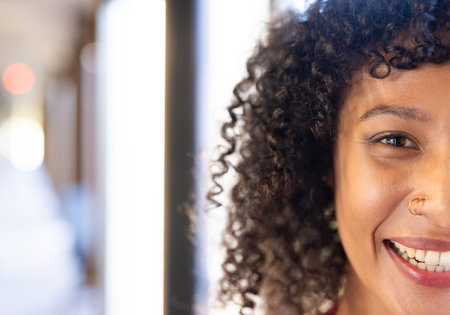 Smiling woman with curly hair in business setting, showcasing positive attitude. professional, success, confidence, positivity, cheerful, corporateの写真素材