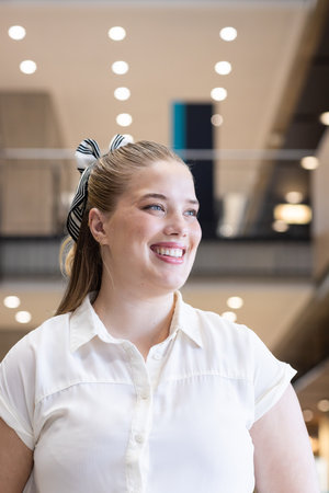 Smiling woman in business attire standing in modern office building. professional, corporate,...