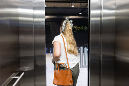 Exiting elevator, woman with handbag walking into modern office building. Business, corporate,...