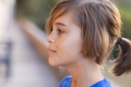 Side profile of school boy with ponytail, looking thoughtful outdoors. childhood, thinking,...