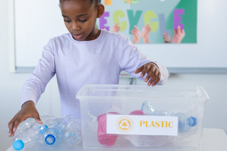 Recycling plastic bottles, african american girl in school classroom. sustainability, conservation,...