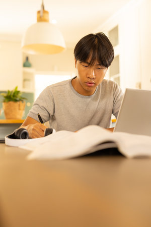 Studying , young man using laptop and writing in notebook. Remote working, e-learning, student,...