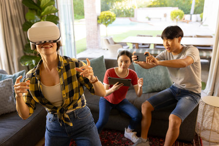 Playing virtual reality game using VR headset, mother with friends watching and recording....