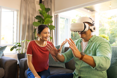 Using VR headset, father interacting while daughter smiling in living room. Technology, virtual...
