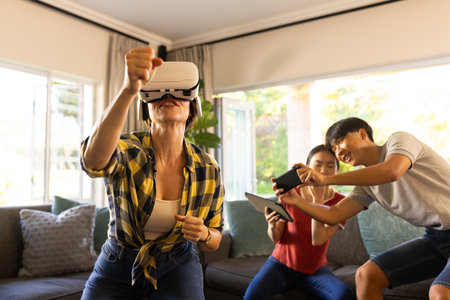 Using VR headset, mother playing game while family members watching and laughing. gaming, laughter, entertainment, technology, fun, interactionの写真素材