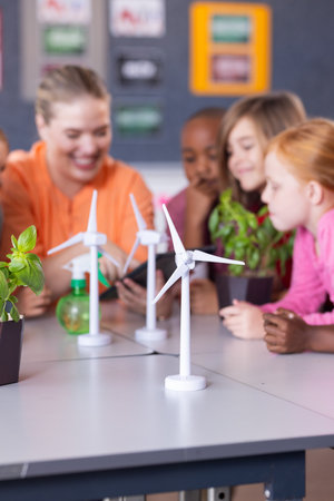 In school, female teacher and diverse students examining wind turbine models and plants together. Education, STEM, learning, sustainability, teaching, environmentの写真素材
