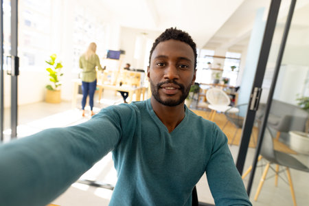 Portrait of happy casual african american businessman looking at camera in modern office. Business, communication, finances and work.の写真素材