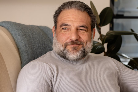 Smiling mature man relaxing at home, enjoying peaceful moment on sofa. Relaxation, leisure,...
