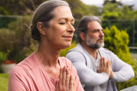 Mature couple meditating outdoors, enjoying peaceful moment in nature together. Wellness, meditation, relaxation, tranquility, harmony, mindfulnessの写真素材