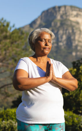 Meditating outdoors, senior woman finding peaceful moment in nature&#39;s serenity. Meditation, relaxation, tranquility, mindfulness, wellness, harmonyの写真素材