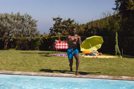 Man running towards pool, enjoying summer day at outdoor party with friends, copy space. poolside,...