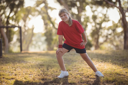 Young girl in red shirt stretching outdoors, smiling and enjoying exercise, copy space. Fitness, active, wellbeing, lifestyle, leisureの写真素材