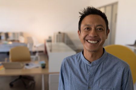 Smiling Asian man in casual shirt standing confidently in modern office, copy space. Business, confidence, professional, workplace, executive, successの写真素材