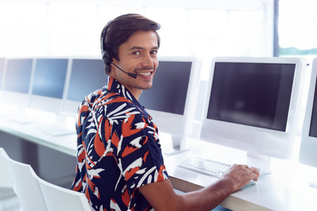 Customer service representative smiling while using headset at computer in office, copy space. Call...